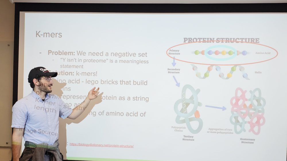 A student presenting a slide about protein structure and k-mers to an audience